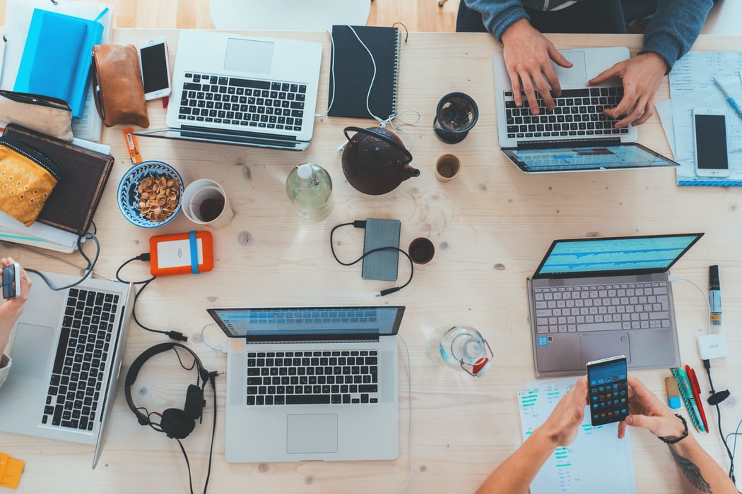 People sitting together on a desk and working individually on their laptops